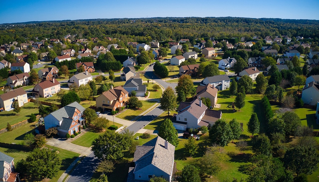 An aerial view of a suburban neighborhood with hundreds of rooftops visible.