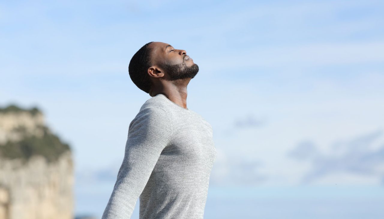 A man on a beach breathing in the salt air